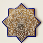 Handcrafted Persian lustreware star tile in Ilkhanid style featuring a golden medallion motif, created in Winter 2025 by the Tavasolian Brothers Workshop